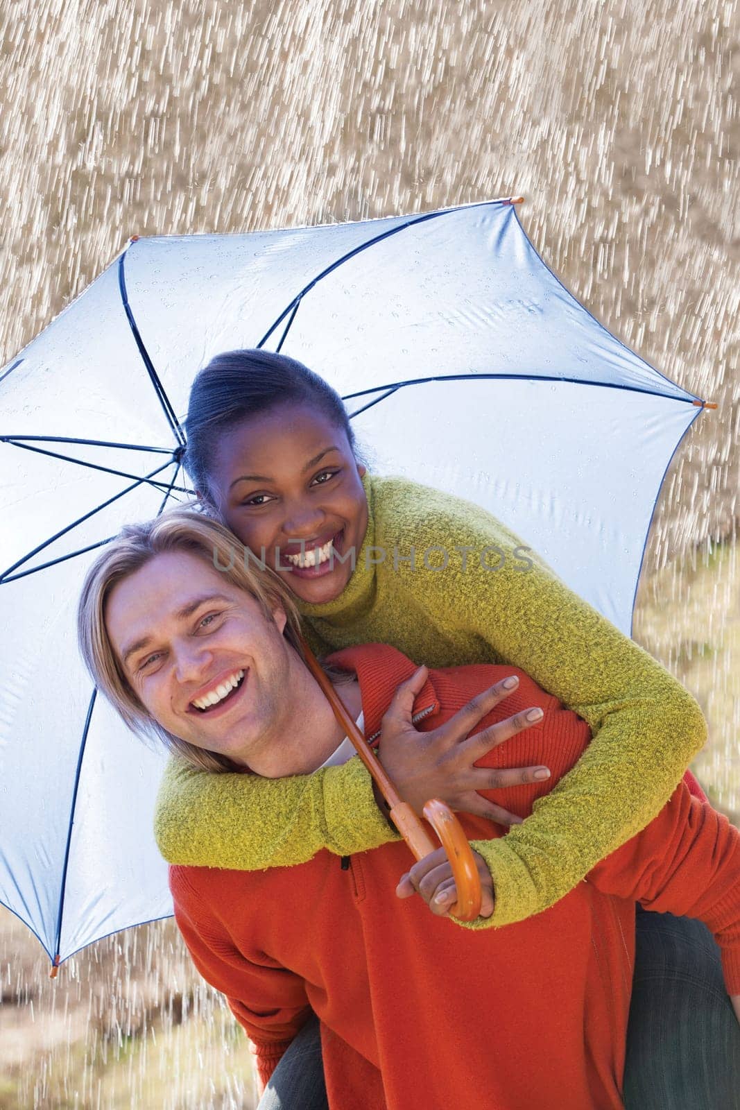 A young couple having fun in the rain under an umbrella