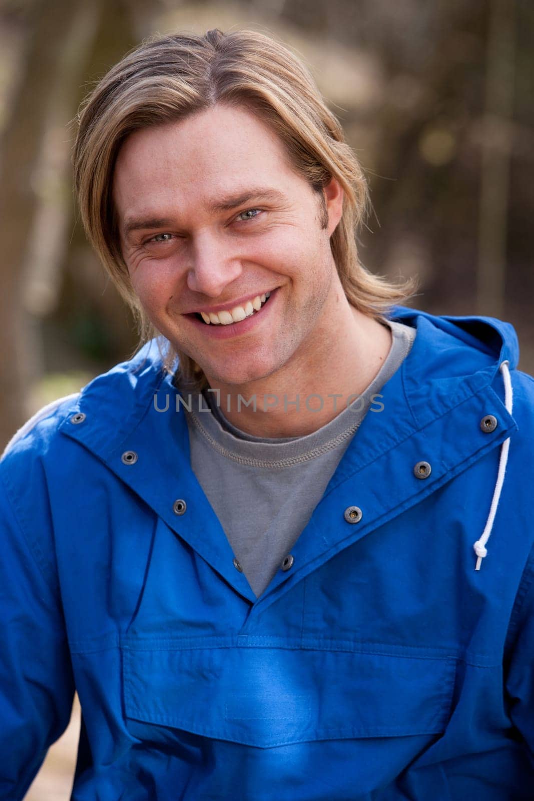 Attractive young man sitting outside. He is smiling at the camera.