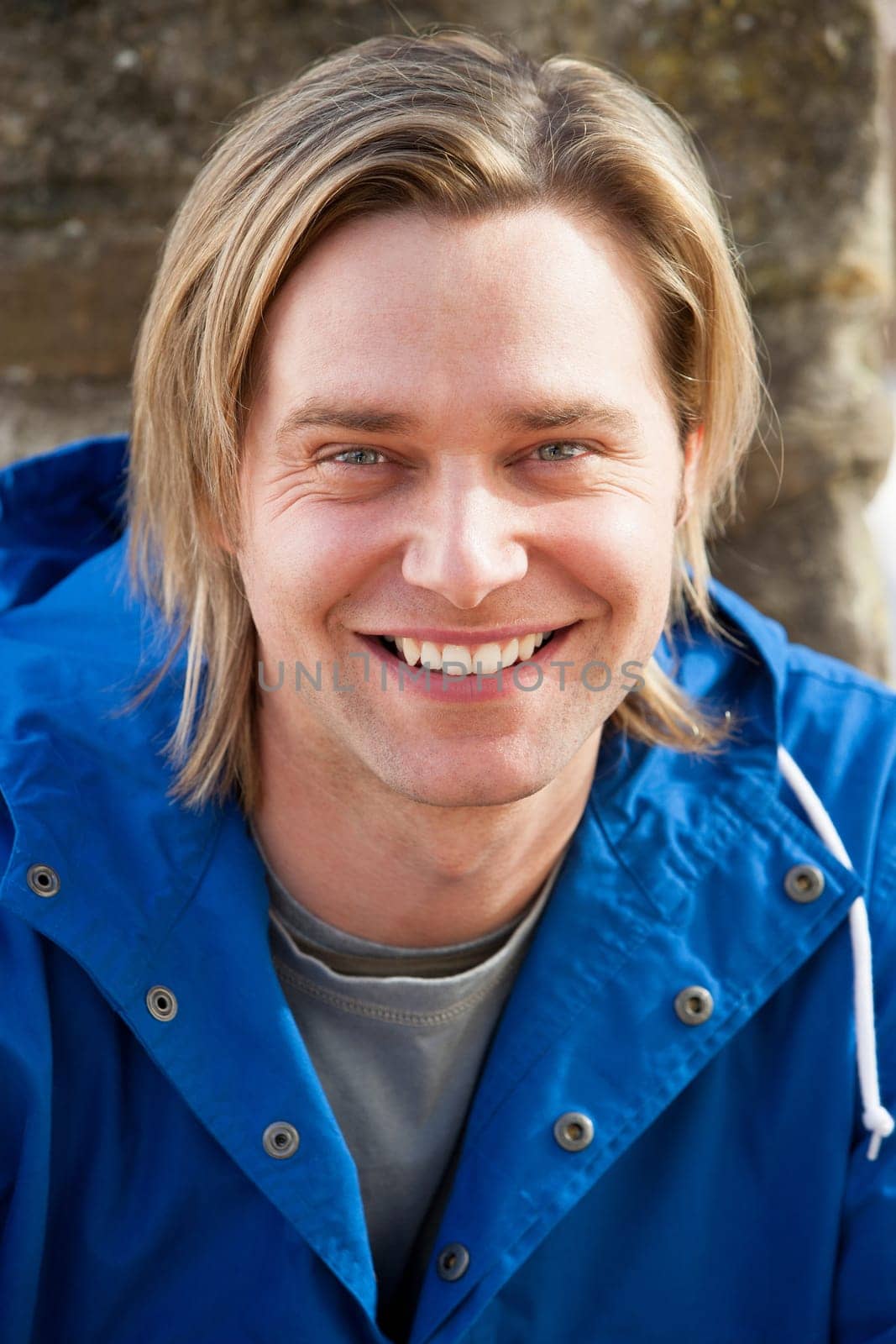 Attractive young man sitting outside. He is smiling at the camera.