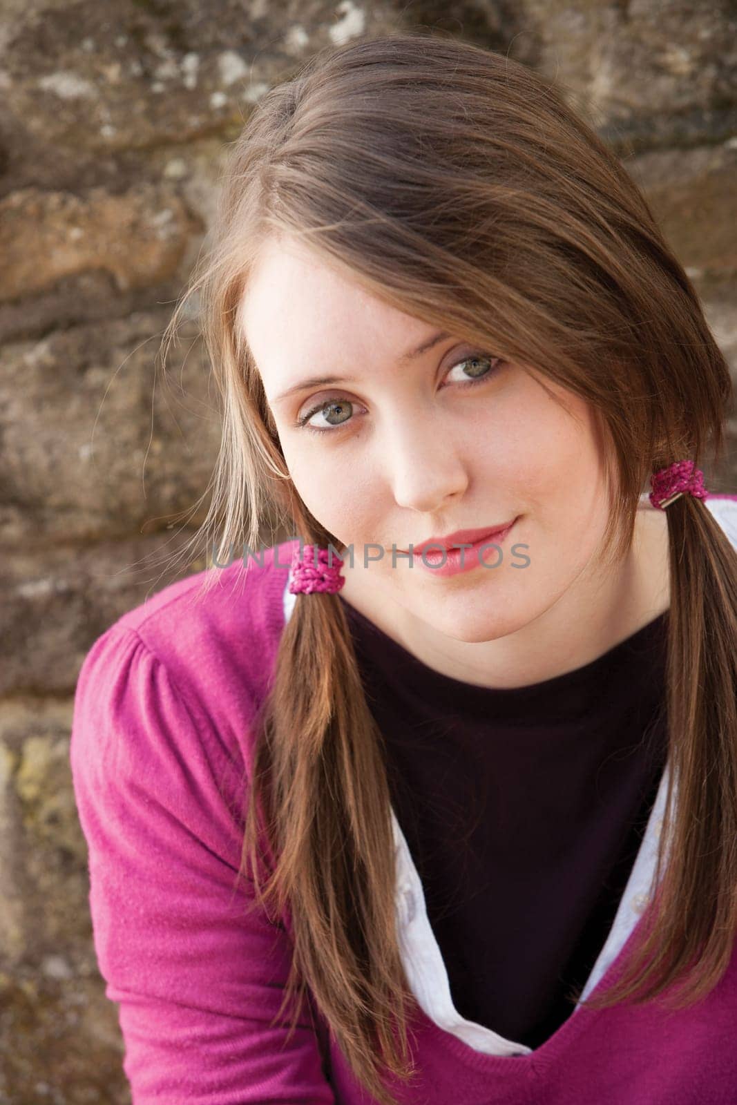 Close up portrait of an attractive young woman sitting outside smiling for the camera