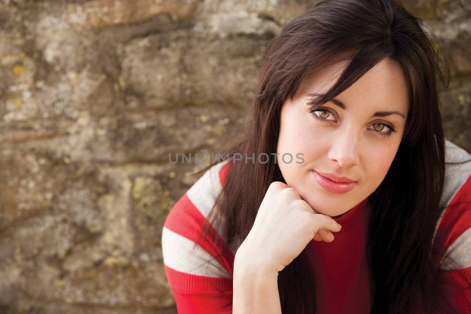 Close up portrait of an attractive young woman sitting outside smiling for the camera