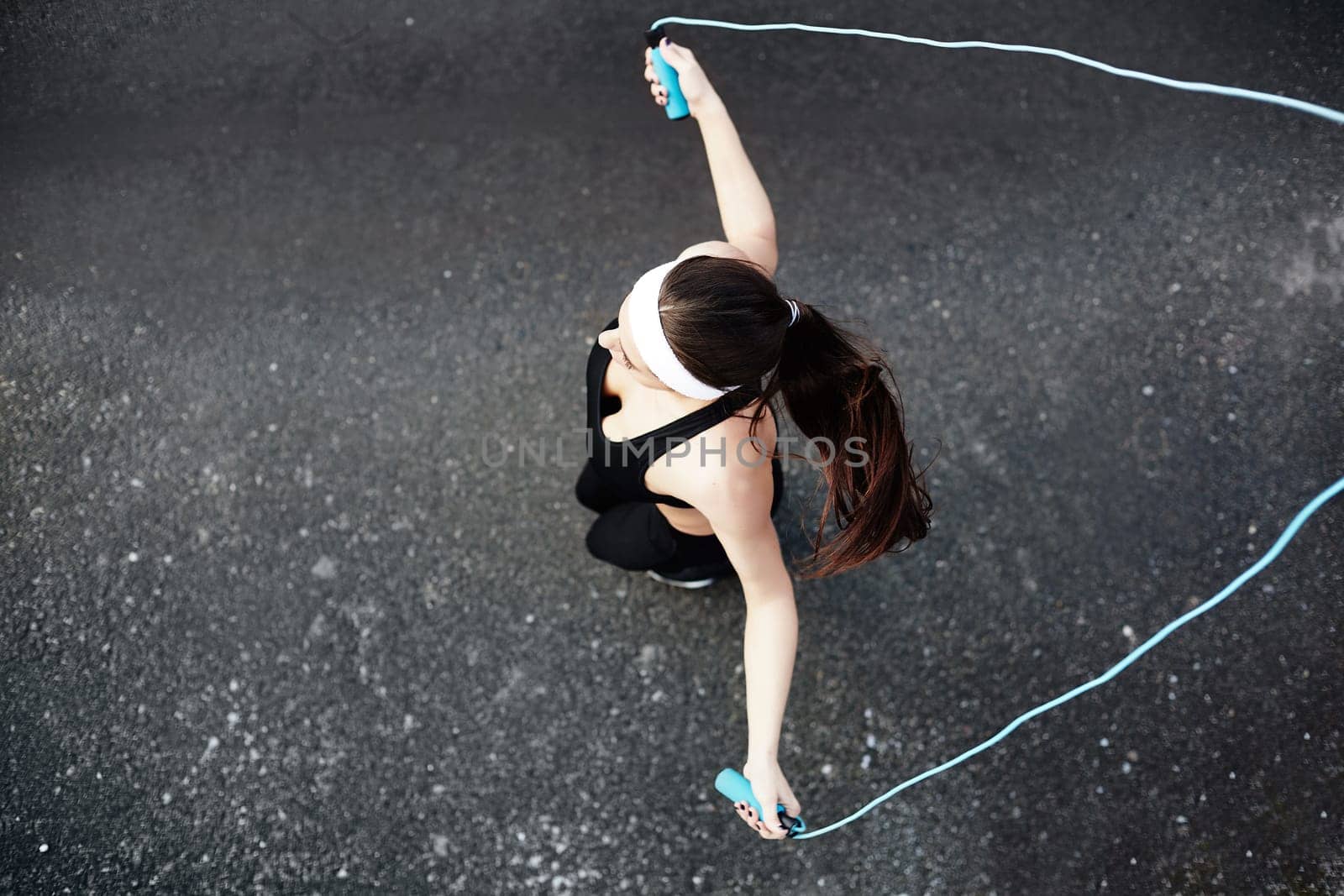 Girl in activewear exercising with skipping-rope