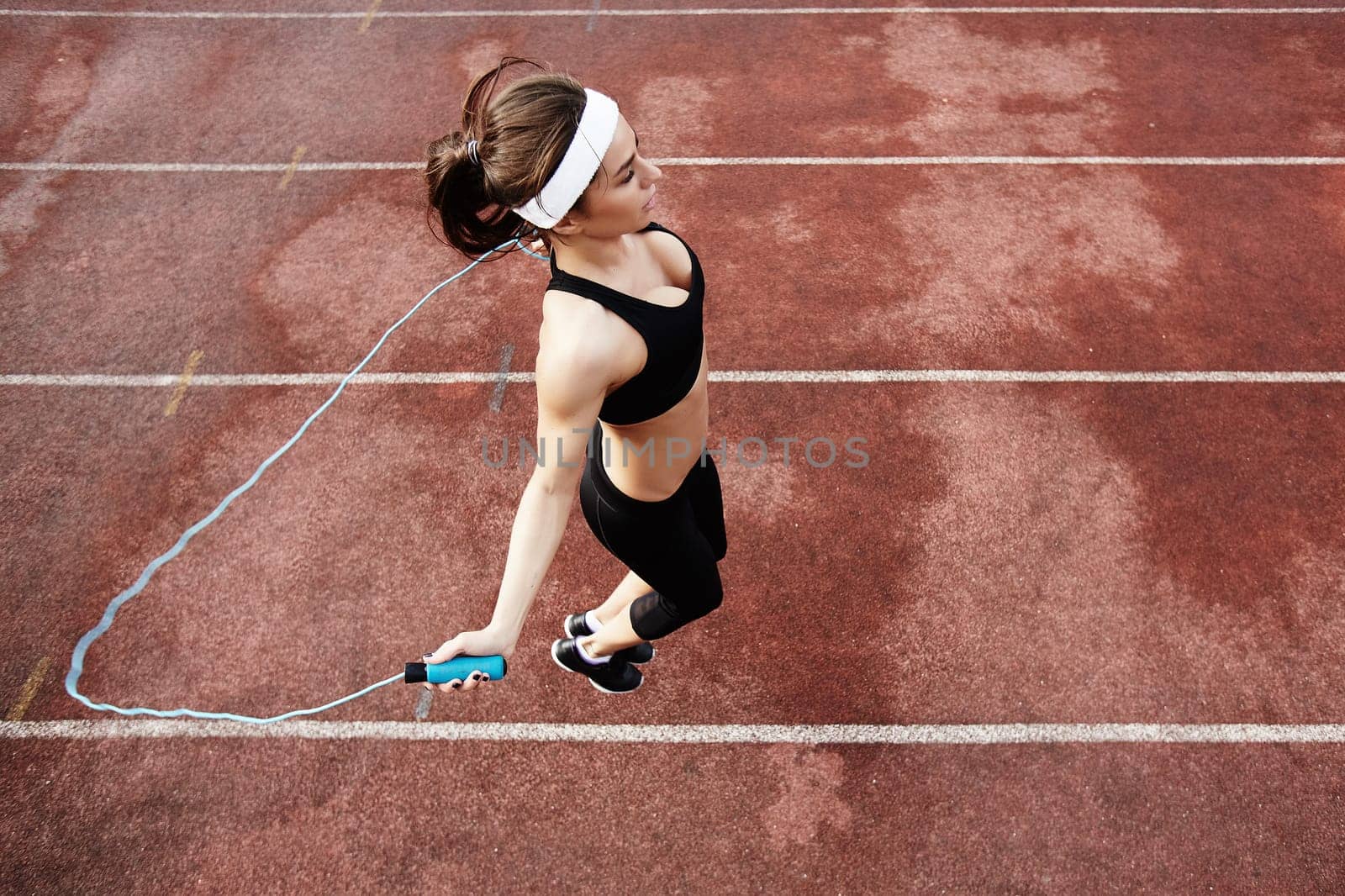 Fit girl exercising with skipping-rope at stadium
