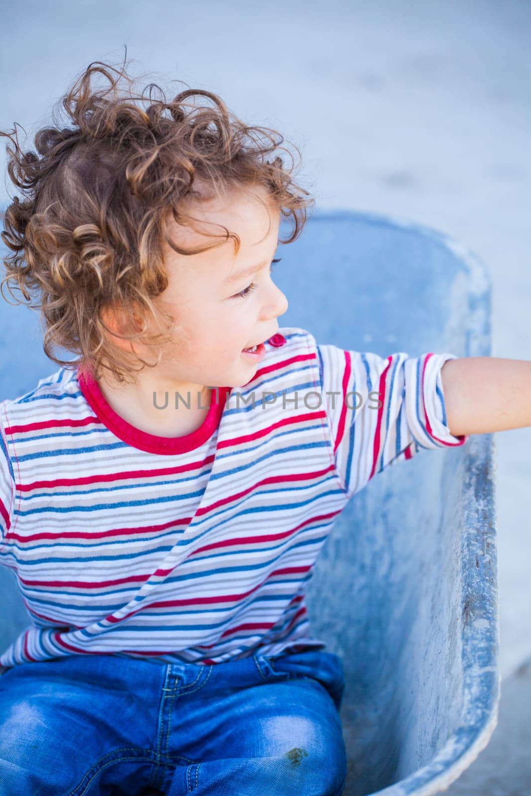 Portrait of 1 year old baby boy playing with a wheel barrow.