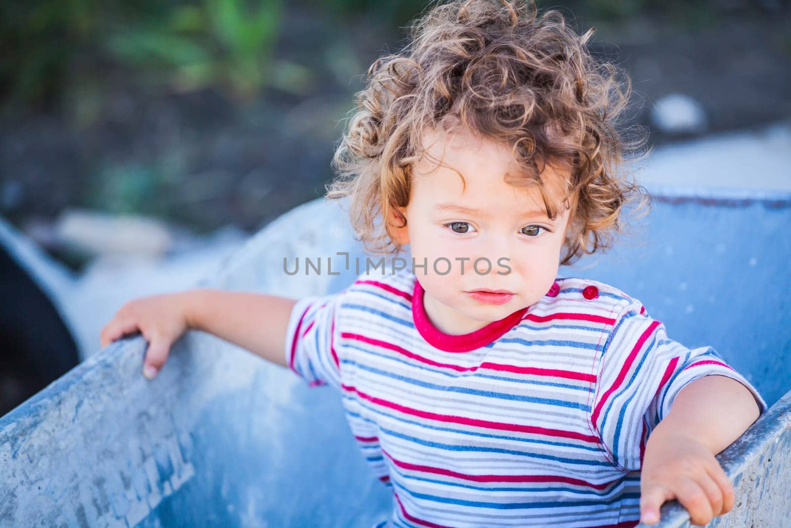 Portrait of 1 year old baby boy playing with a wheel barrow.
