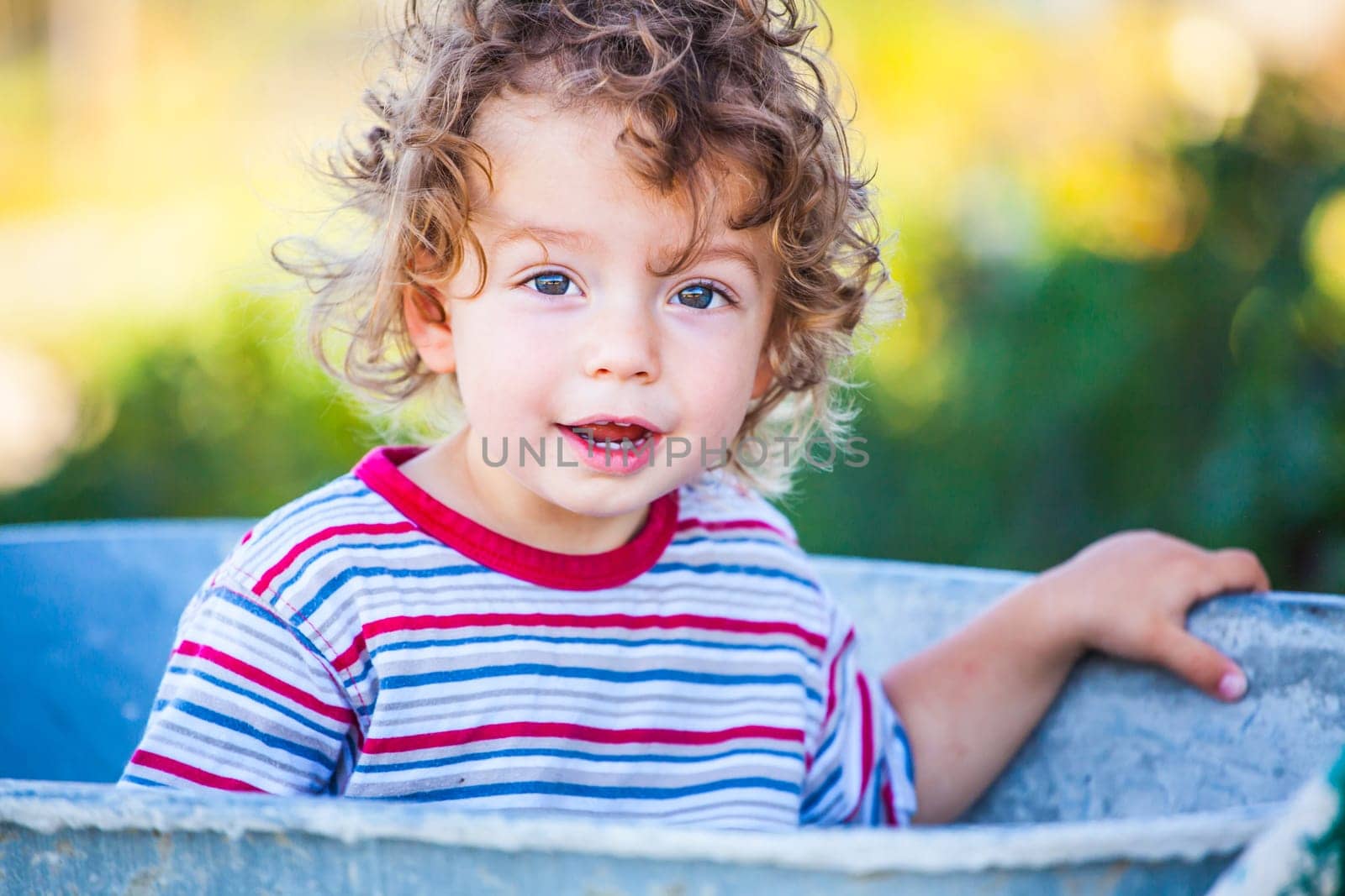 Portrait of 1 year old baby boy playing with a wheel barrow.