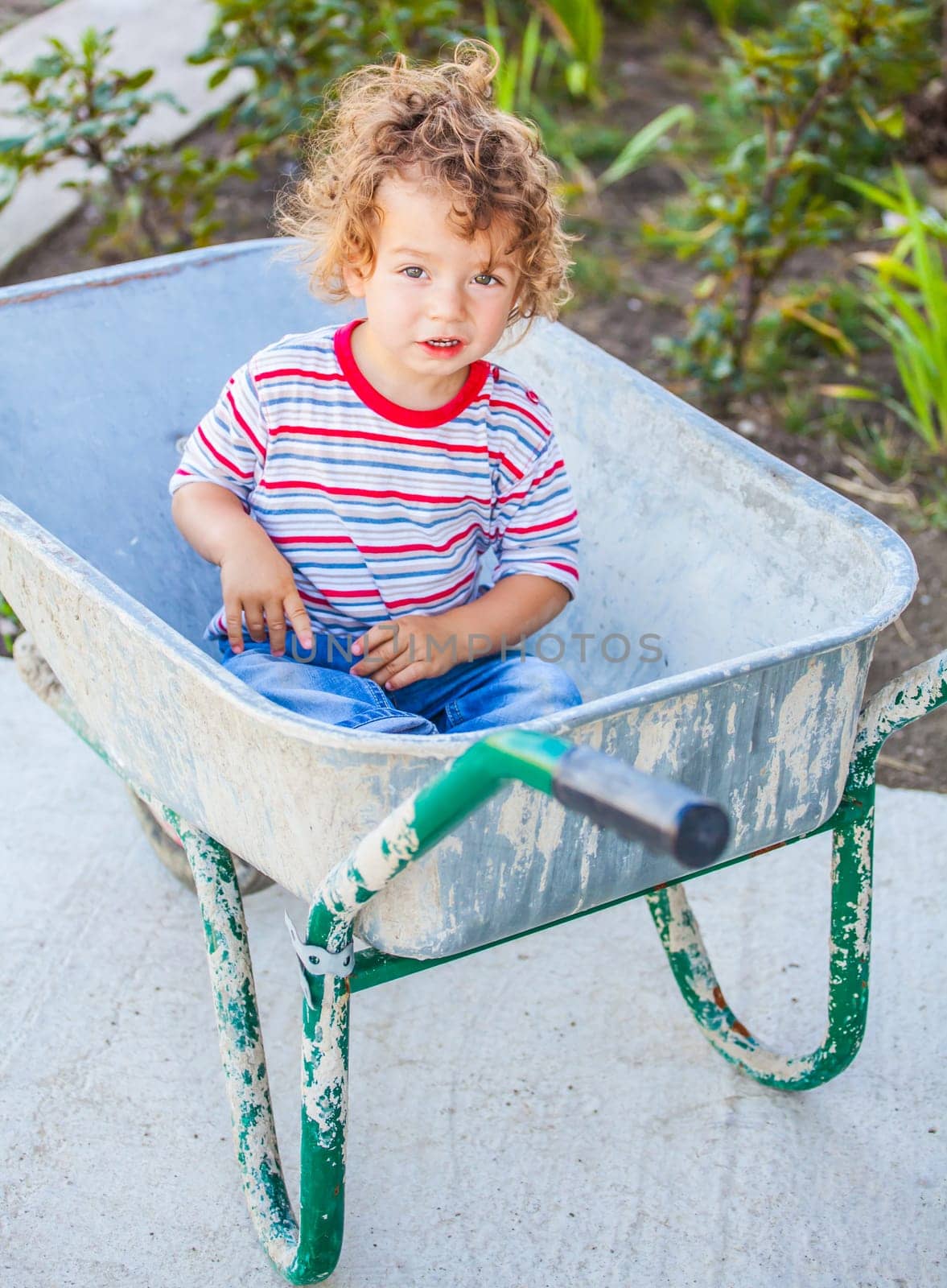 Portrait of 1 year old baby boy playing with a wheel barrow.