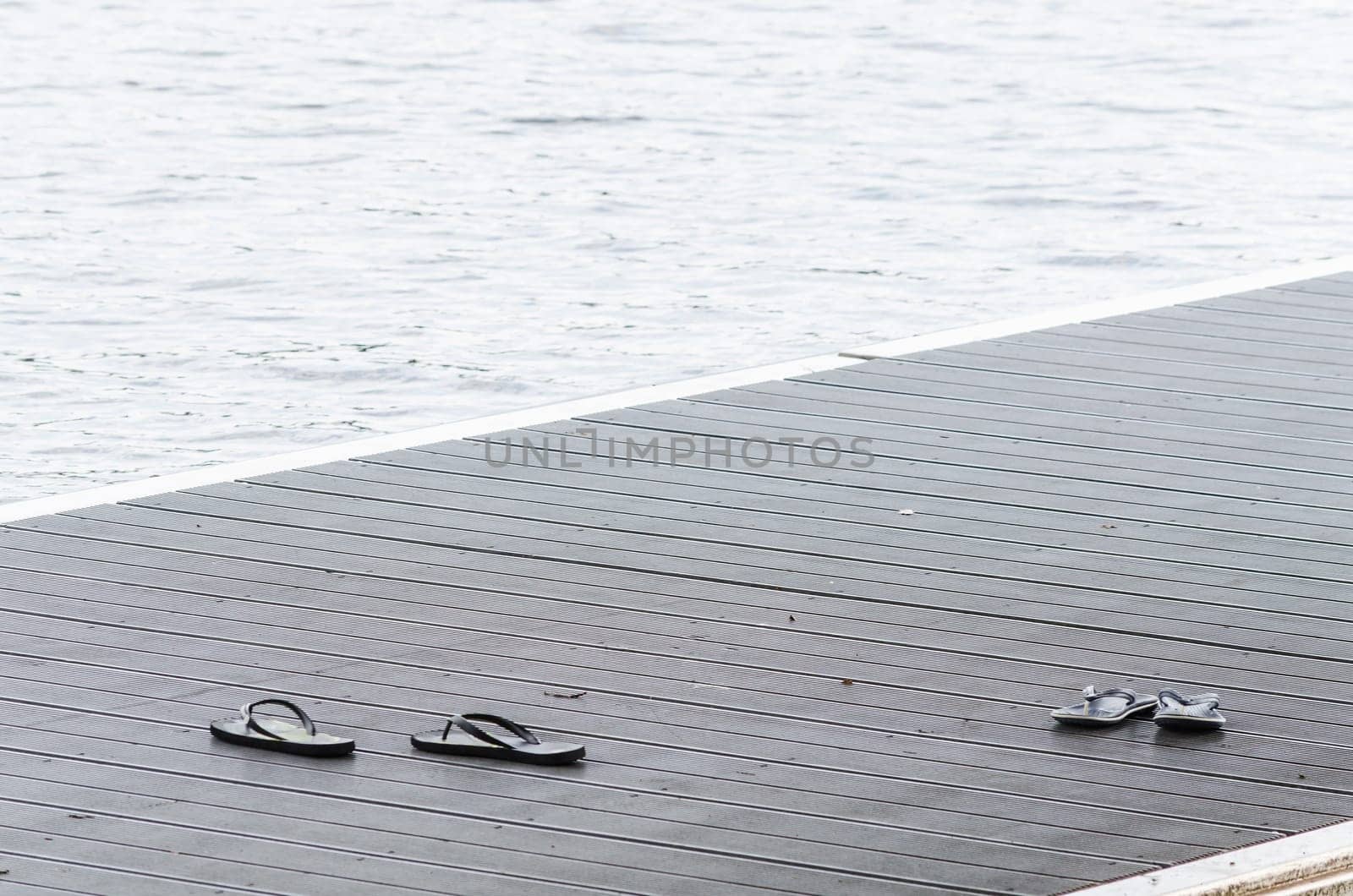 Black sandals on a jetty on a lakeside promenade.