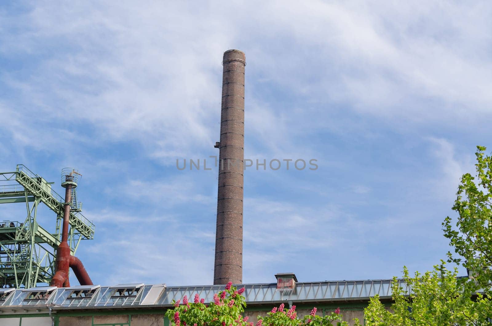 Large factory chimney of an old factory in front of blue sky.