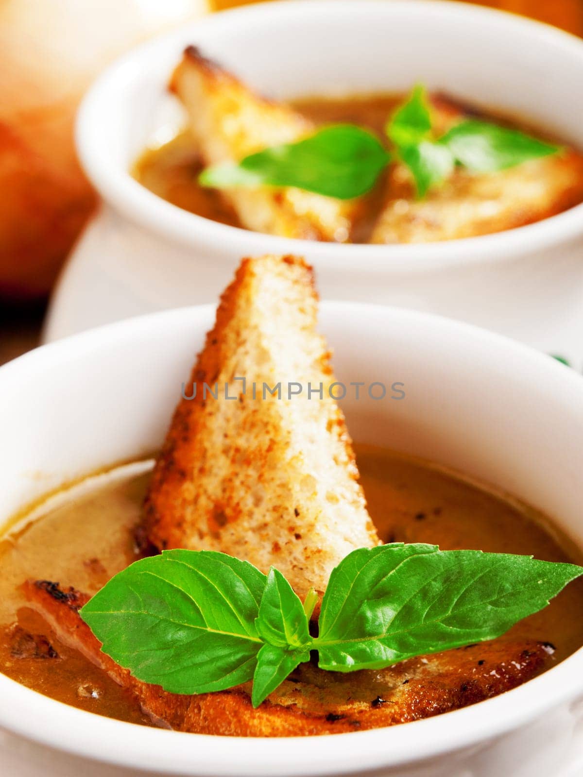 Famous onion soup with onions and olive oil in the background, close up