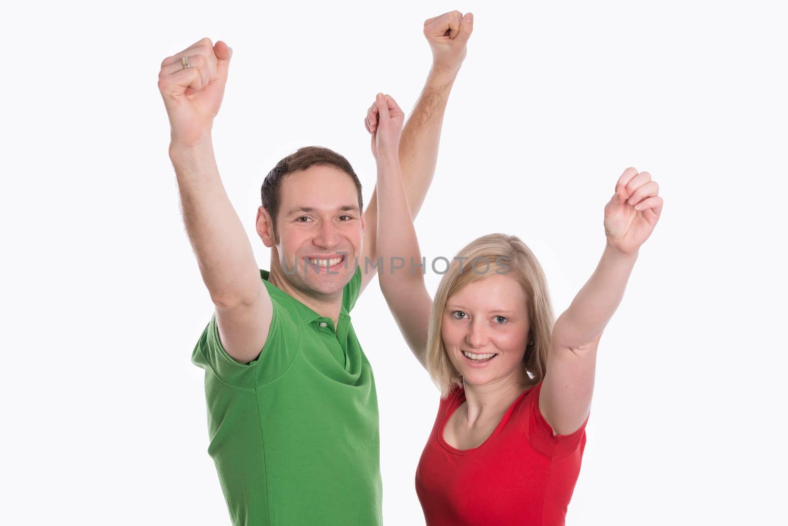 young happy couple in front of white background with arms up