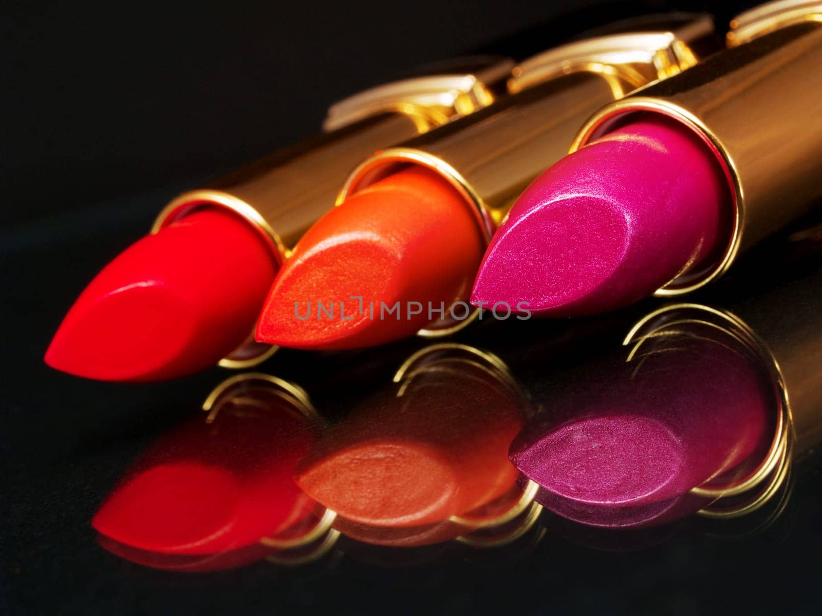 3 Lipsticks on black background with mirror