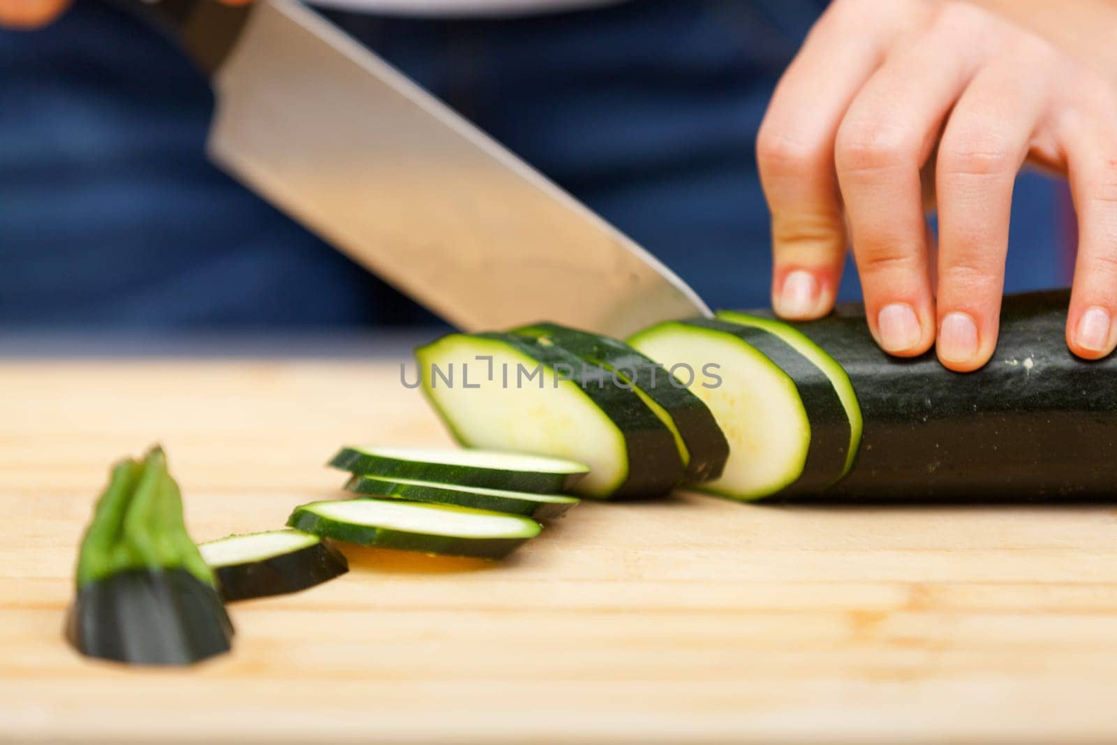 Young woman cutting zucchini in the kitchen