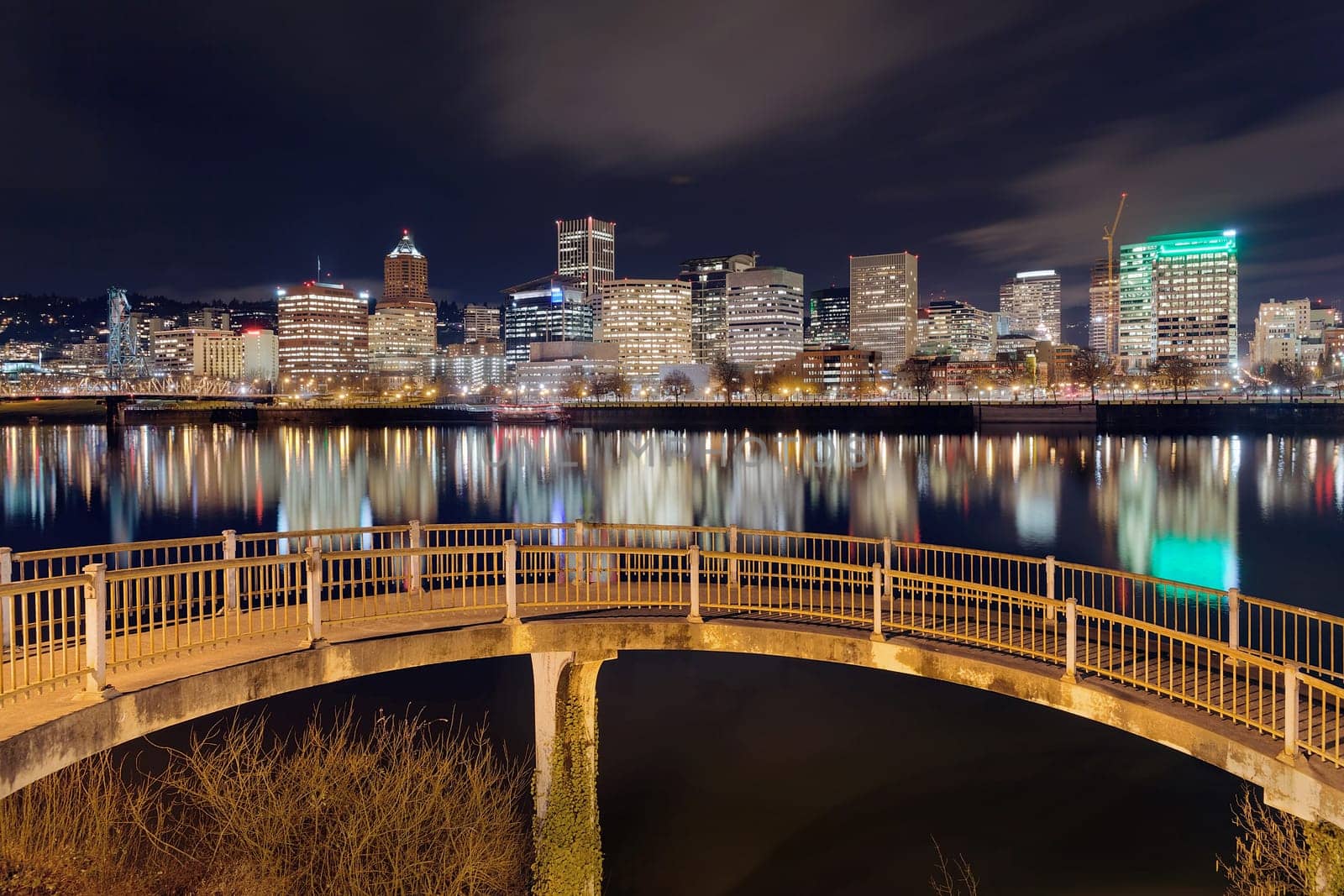 Portland Oregon downtown city skyline from pedestrian bridge along Willamette River at night