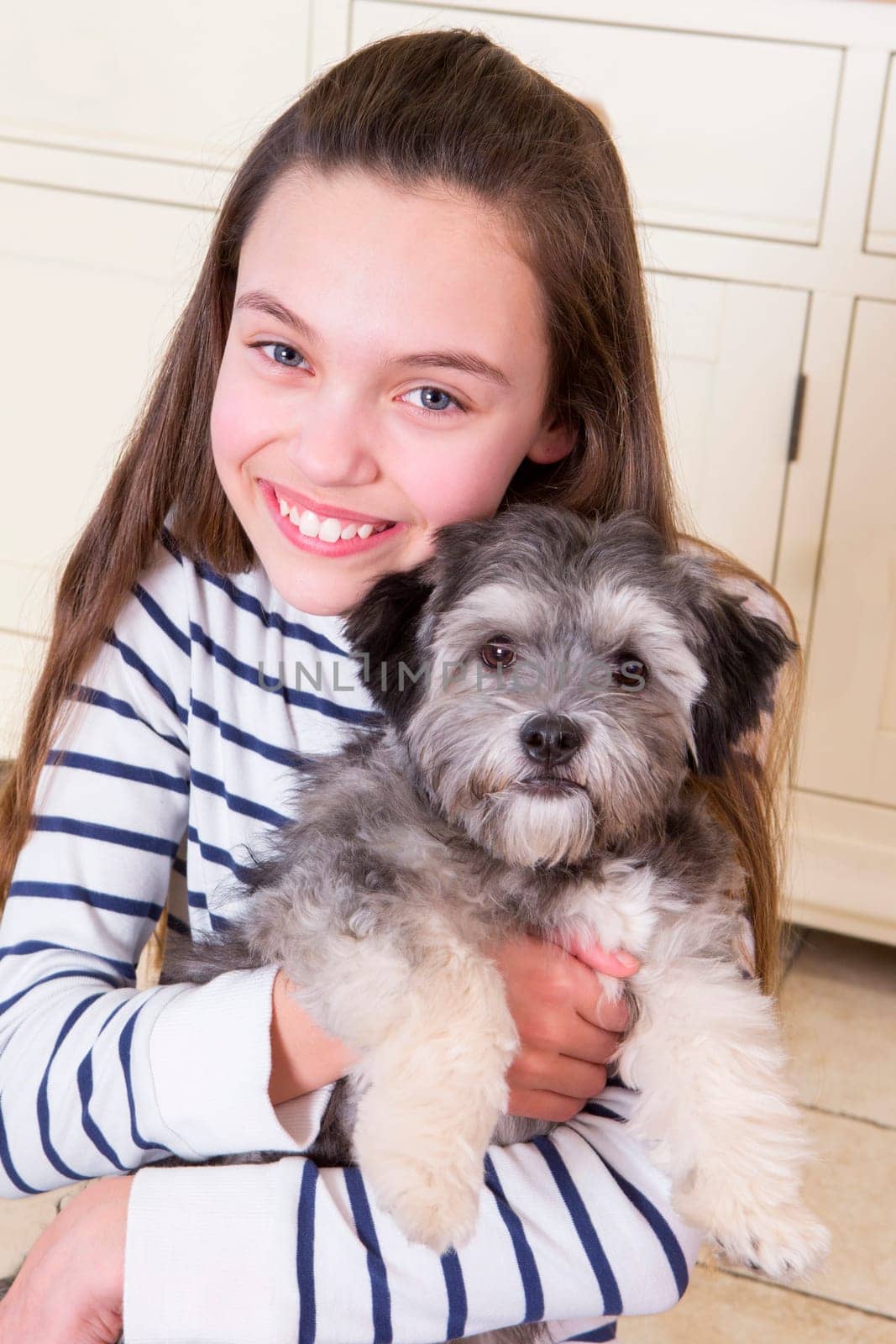 Young girl holding a Puppy. She is looking at the Camera and smiling.