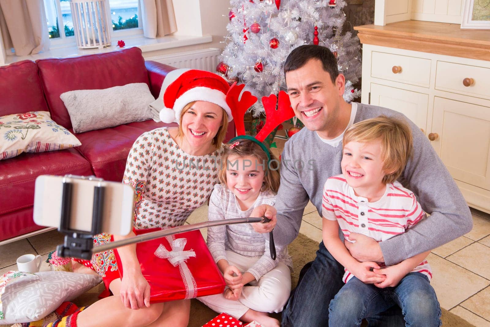 Two Generation Family taking a Selfie at Christmas. They are using a Selfie Stick and Smiling at the Camera.