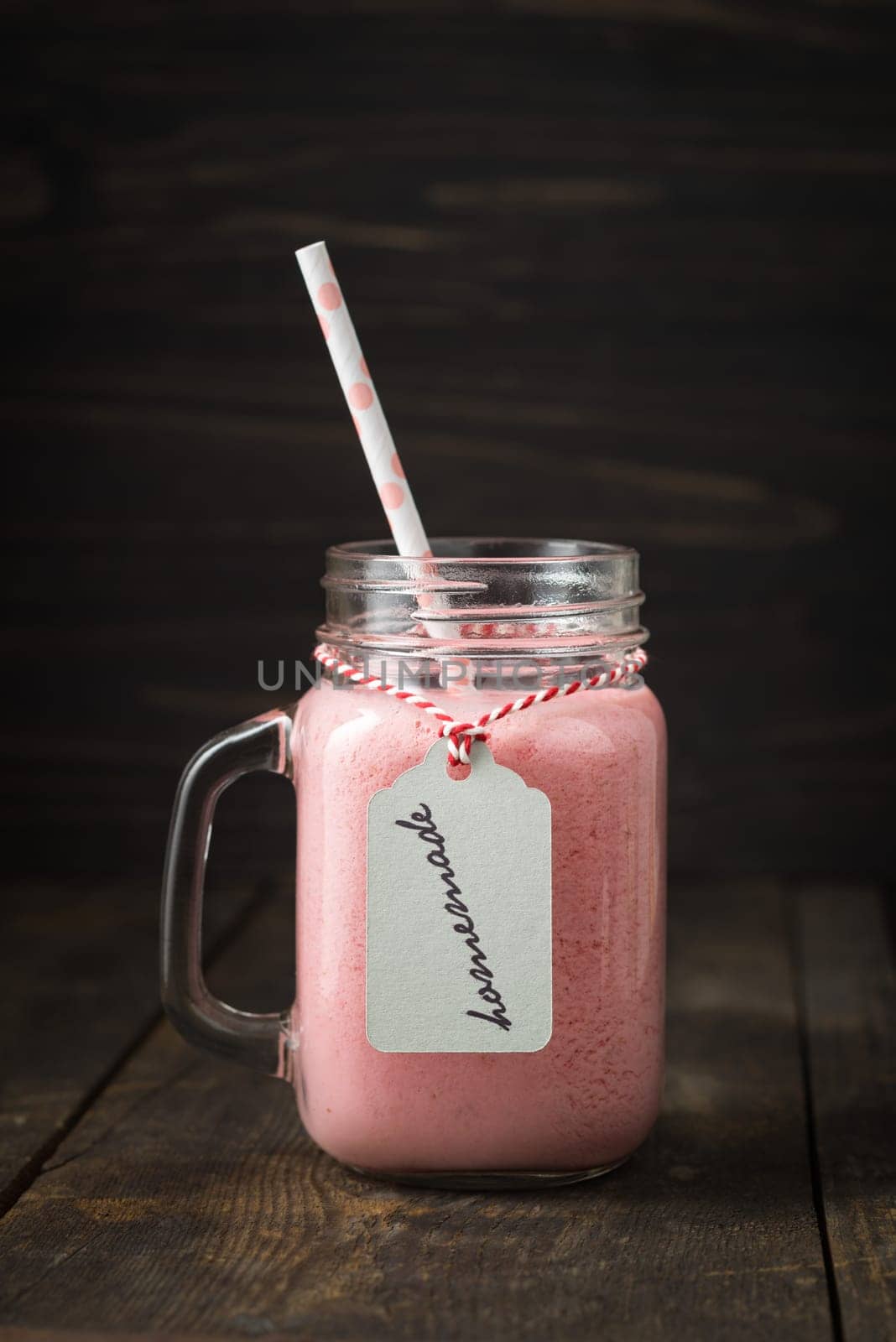 Pink healthy smoothie with yoghurt and berries in glass with pendant with handwritten homemade lettering