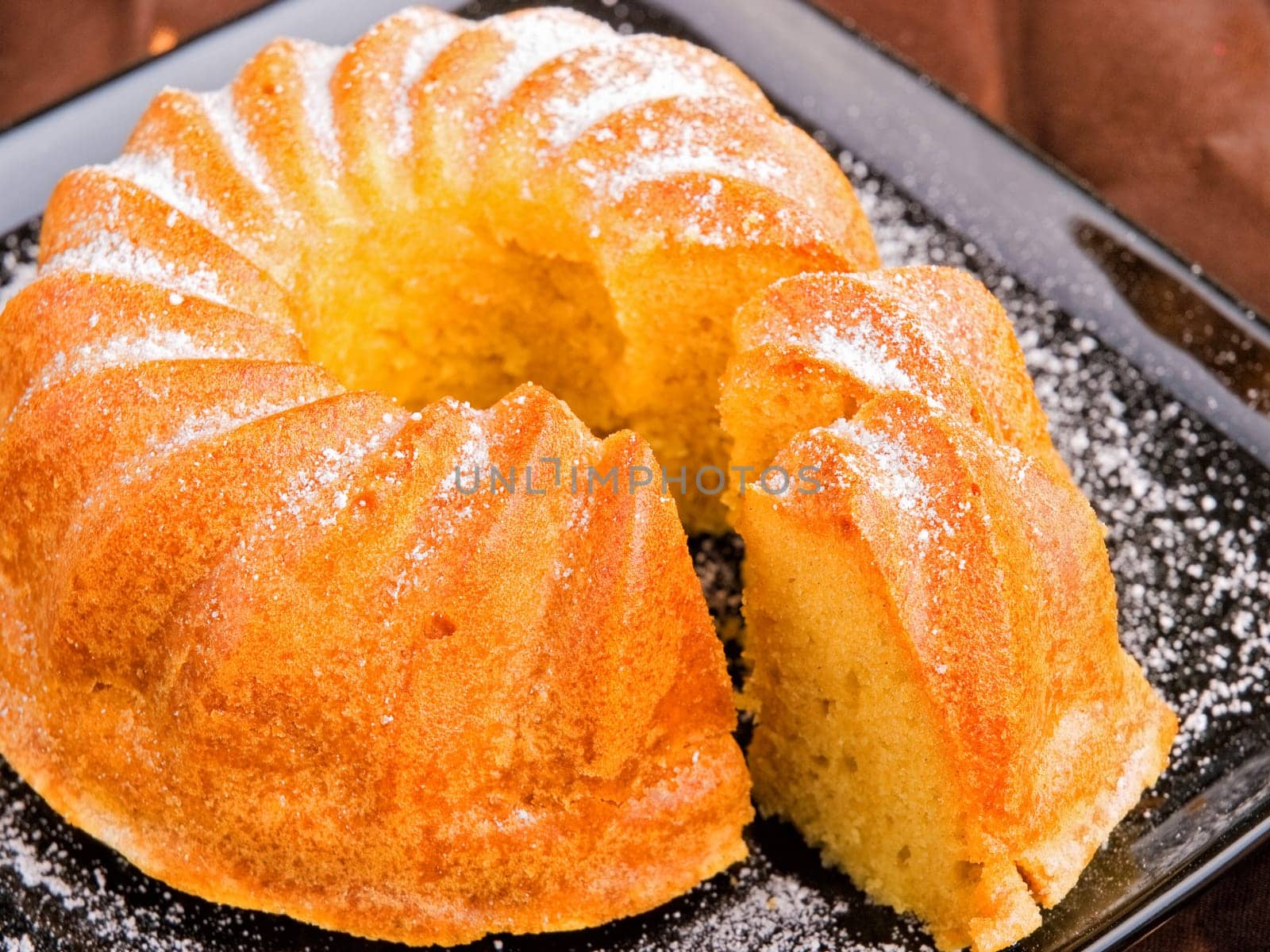 Vanilla cake with one piece of it on brown background