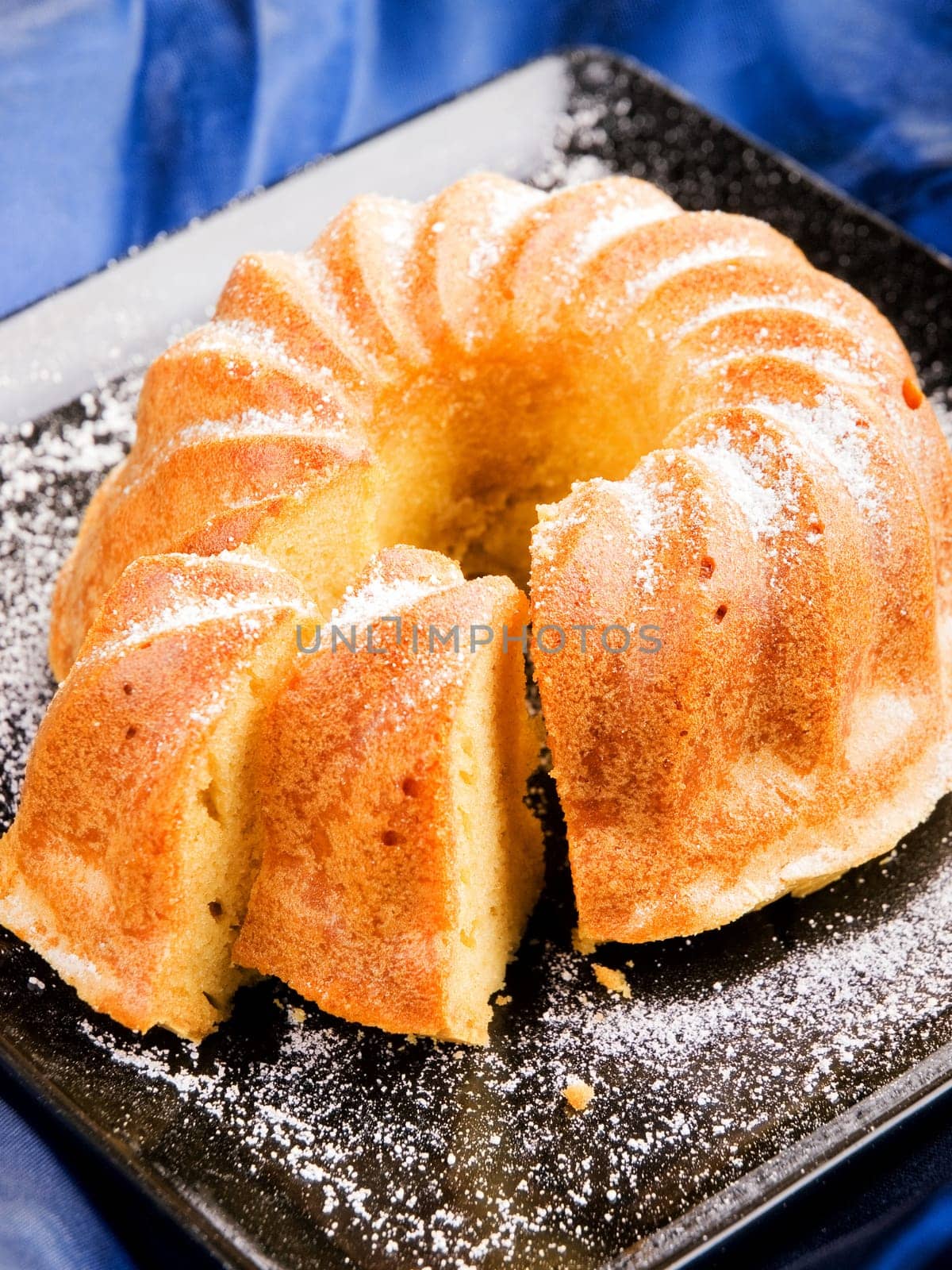 Vanilla cake with one piece of it on brown background