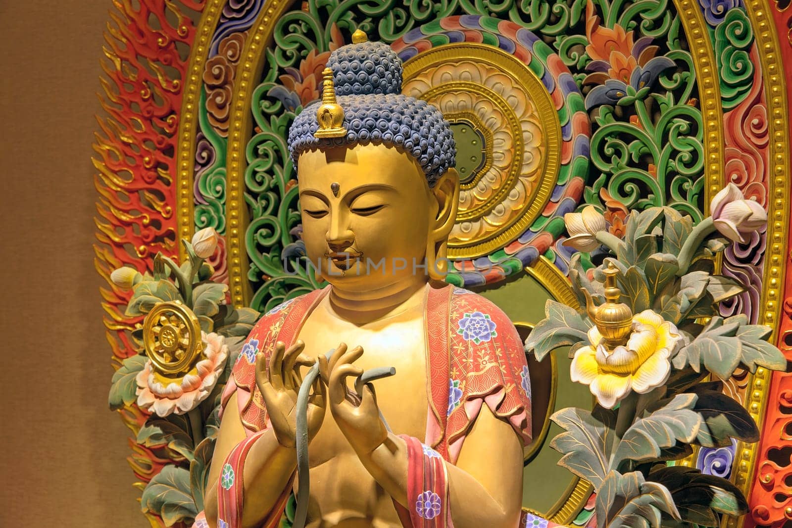 Wood Carved Colorful Sitting Buddha Statue with Intricate Colorful Background Closeup