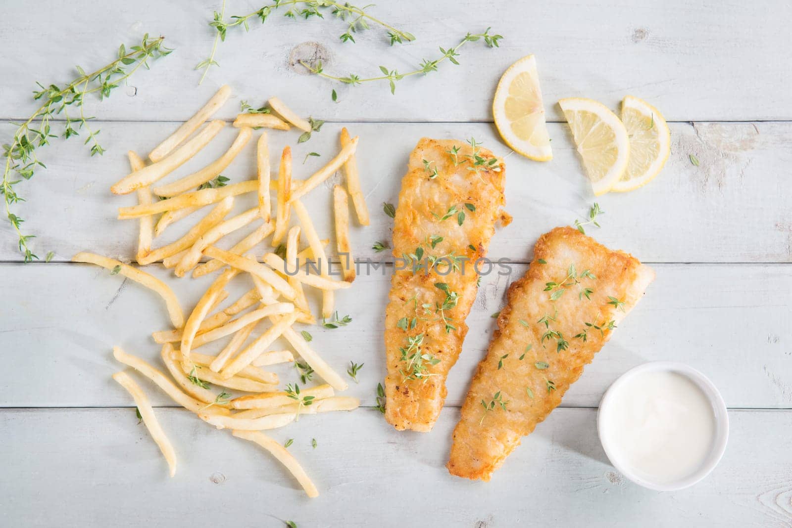 Fish and chips. Top view fried fish fillet with french fries on wooden background.