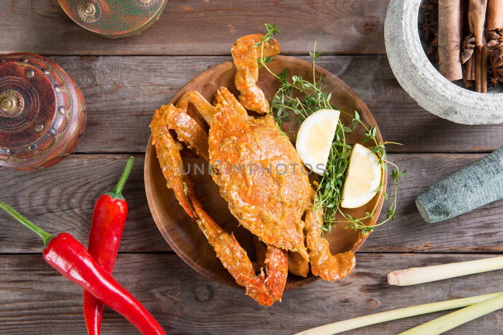 Top view cooked delicious hot and spicy sauce blue crab and ingredients, on wooden background. Fresh cook with hot smoke steams.