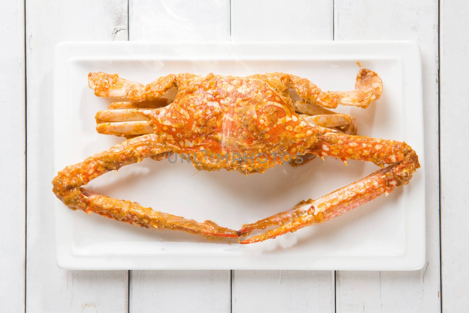 Close up top view cooked delicious hot and spicy sauce blue crab on white plate. Fresh cook with hot smoke steams.