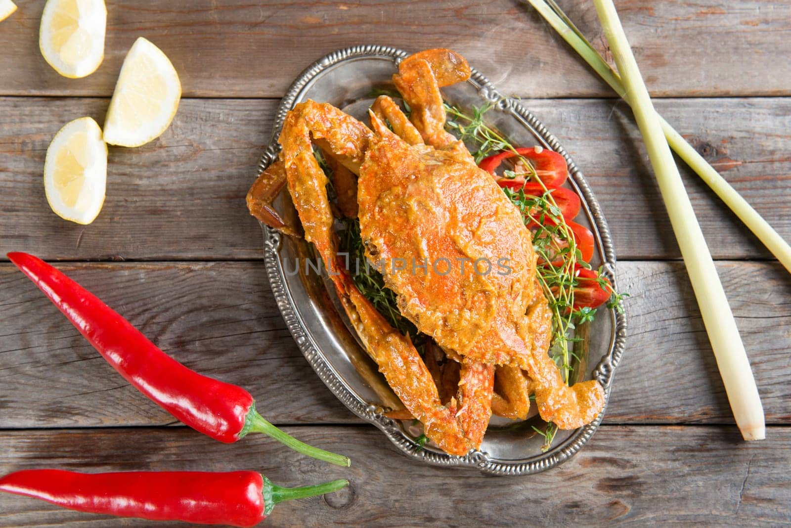 Top view cooked delicious hot and spicy sauce blue crab and ingredients, on old wooden background. Fresh cook with hot smoke steams.