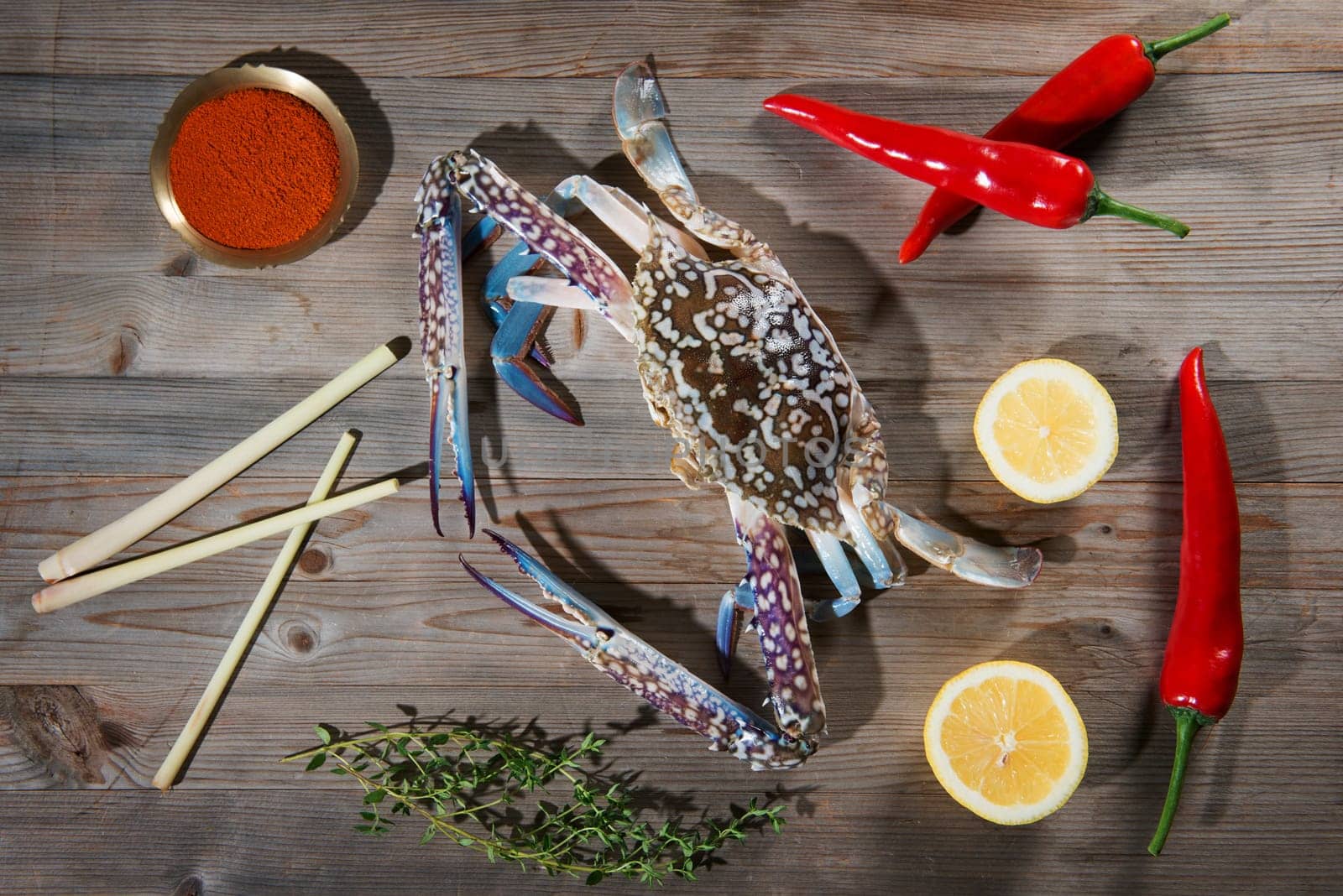 Above view raw blue crab and ingredients ready to cook, on wood background.