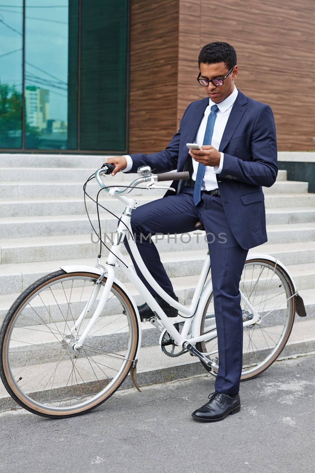 Elegant businessman using cellphone while sitting on bicycle