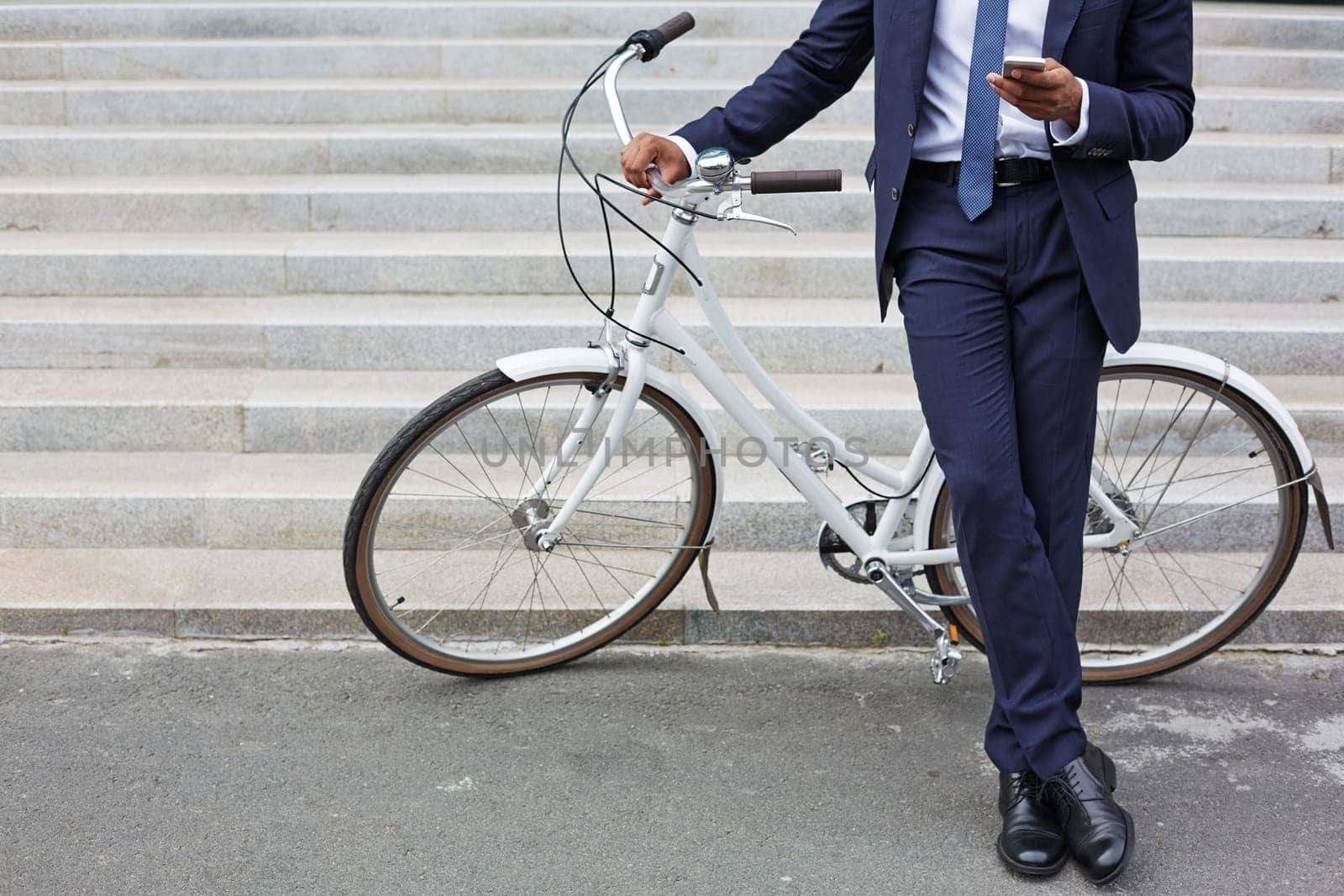 Businessman with cellphone standing by bicycle