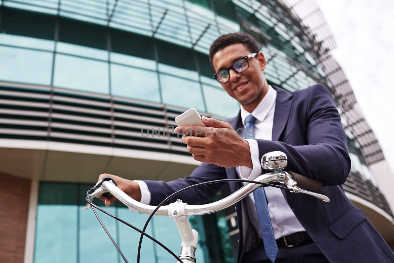 Young businessman on bicycle reading sms in urban environment