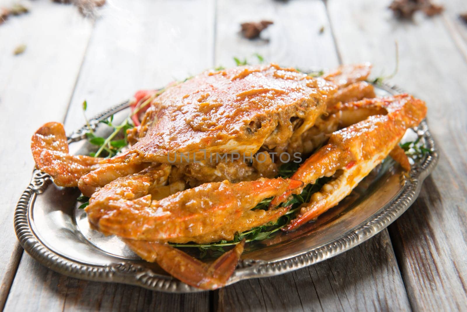 Cooked delicious hot and spicy sauce blue crab, on wooden background. Fresh cook with hot smoke steams.