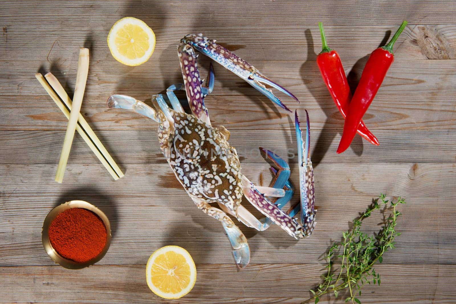 Top view raw blue crab and ingredients ready to cook, on wood background.