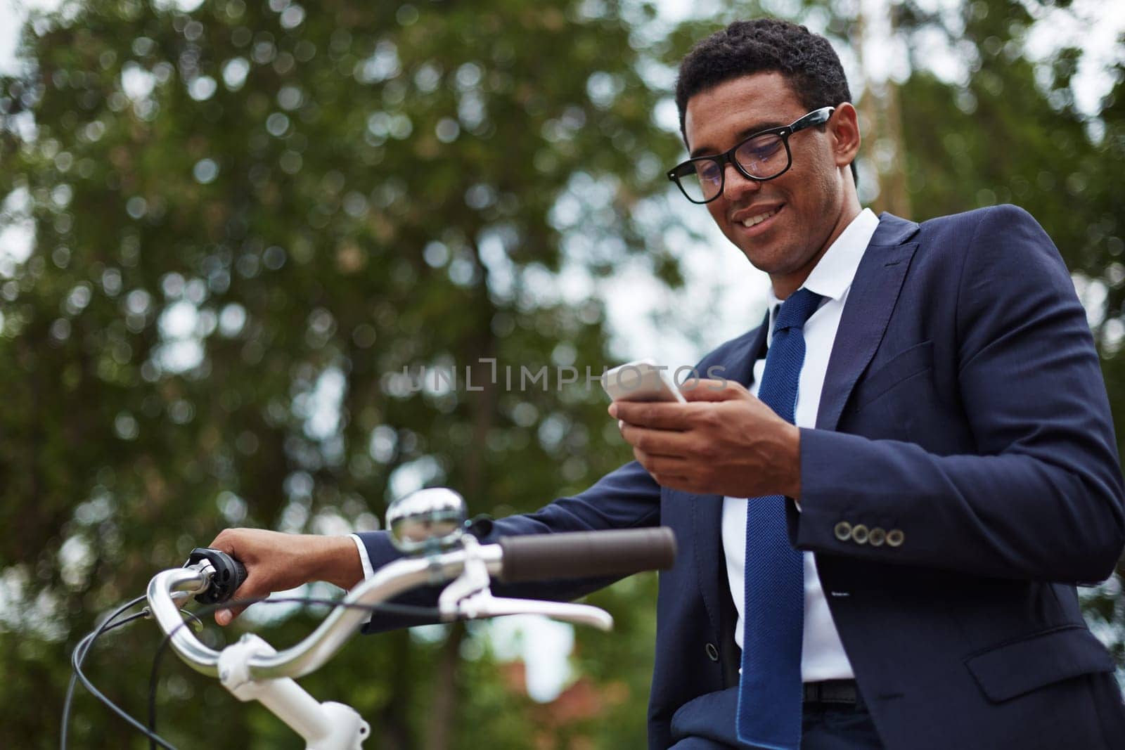 Happy modern businessman using cellphone in park