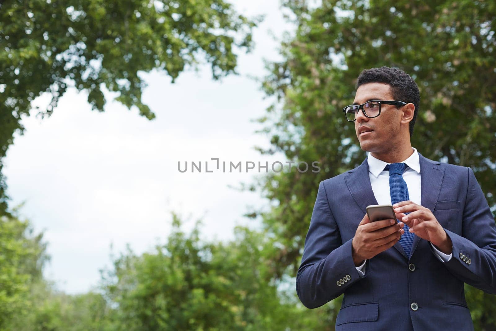 Young businessman with cellphone working in park