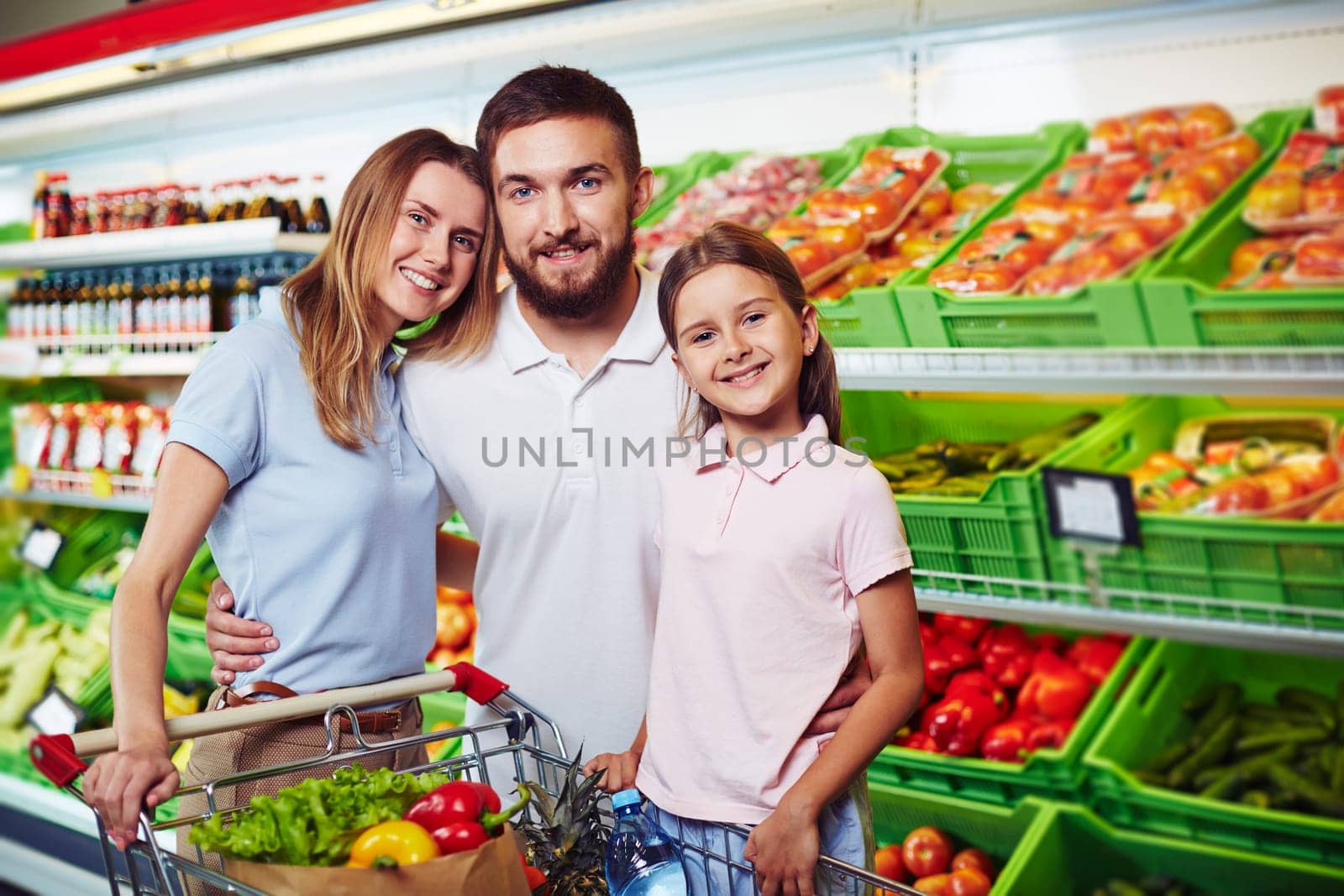 Family of three looking at camera in supermarket