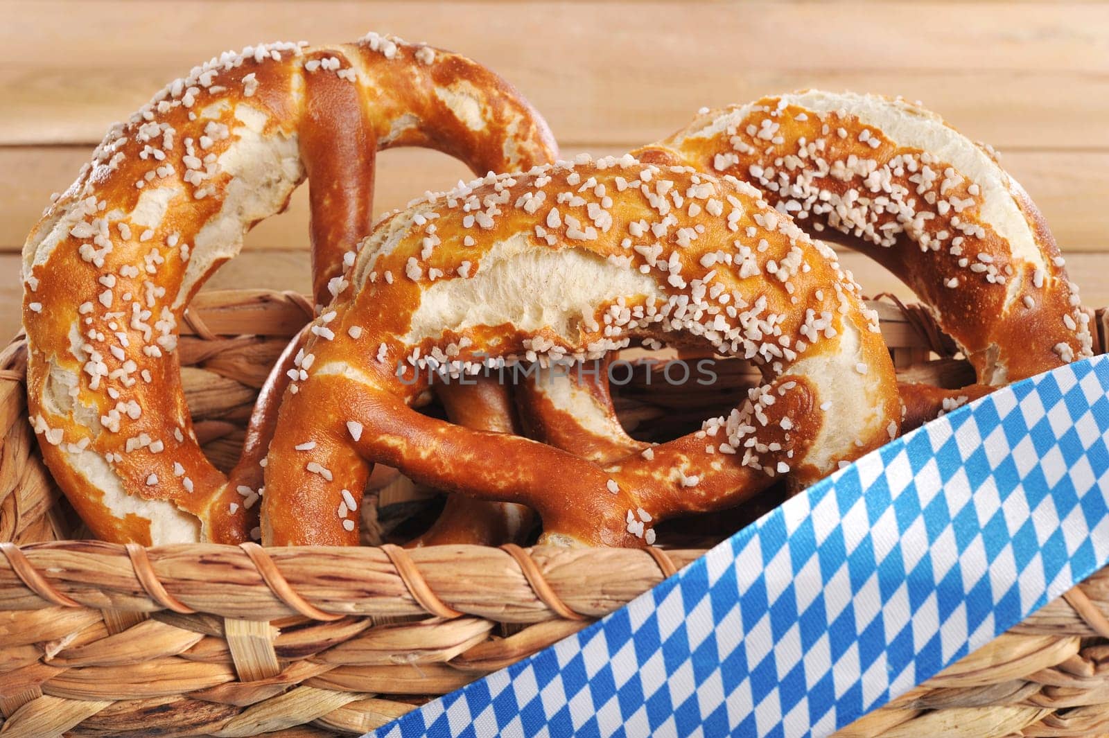 Three original Bavarian lye pretzels with salt in front of a wooden wall