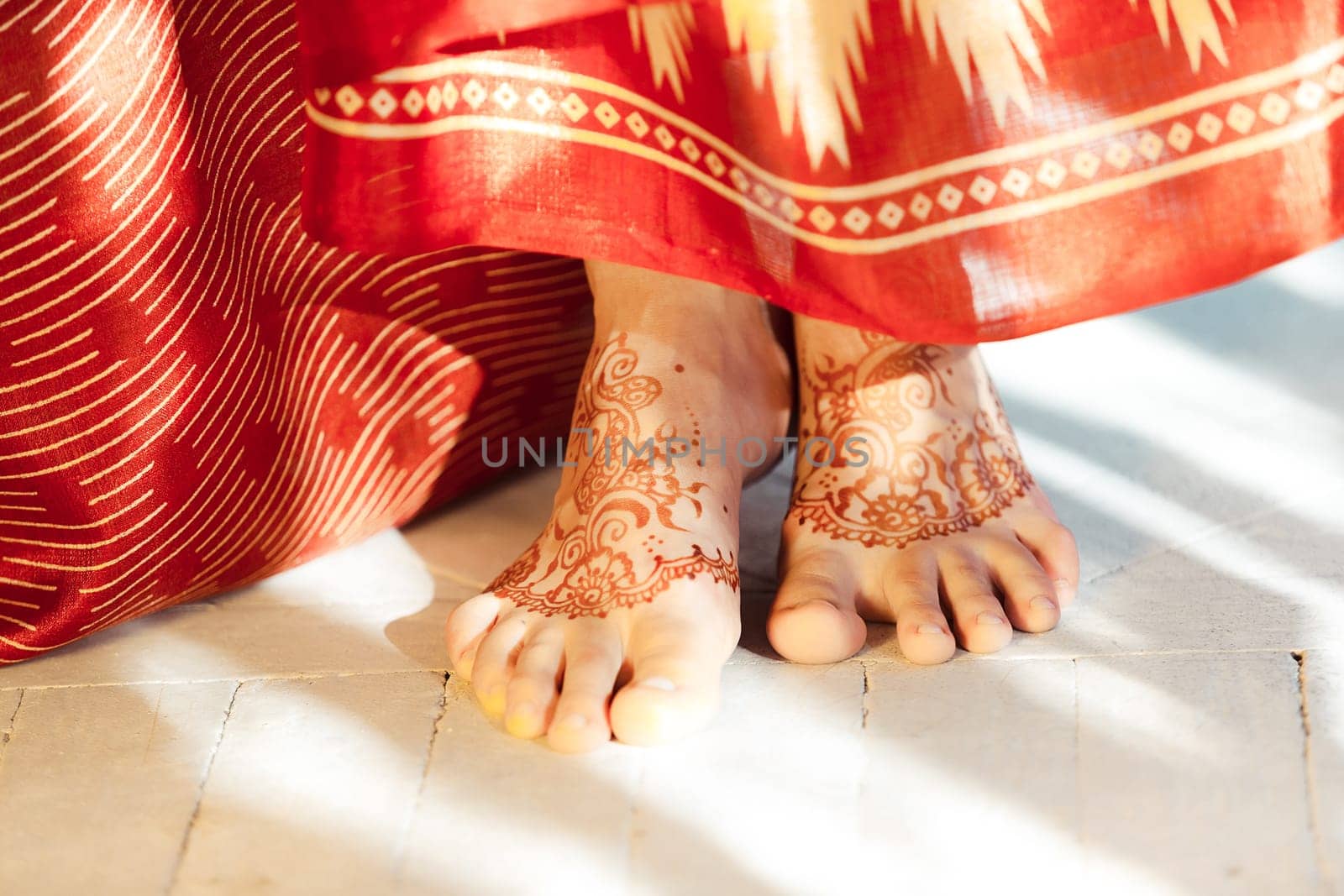Indian picture on woman feet, mehendi tradition decoration, resistant design by special paint, brown henna.  Indian red dress on white background