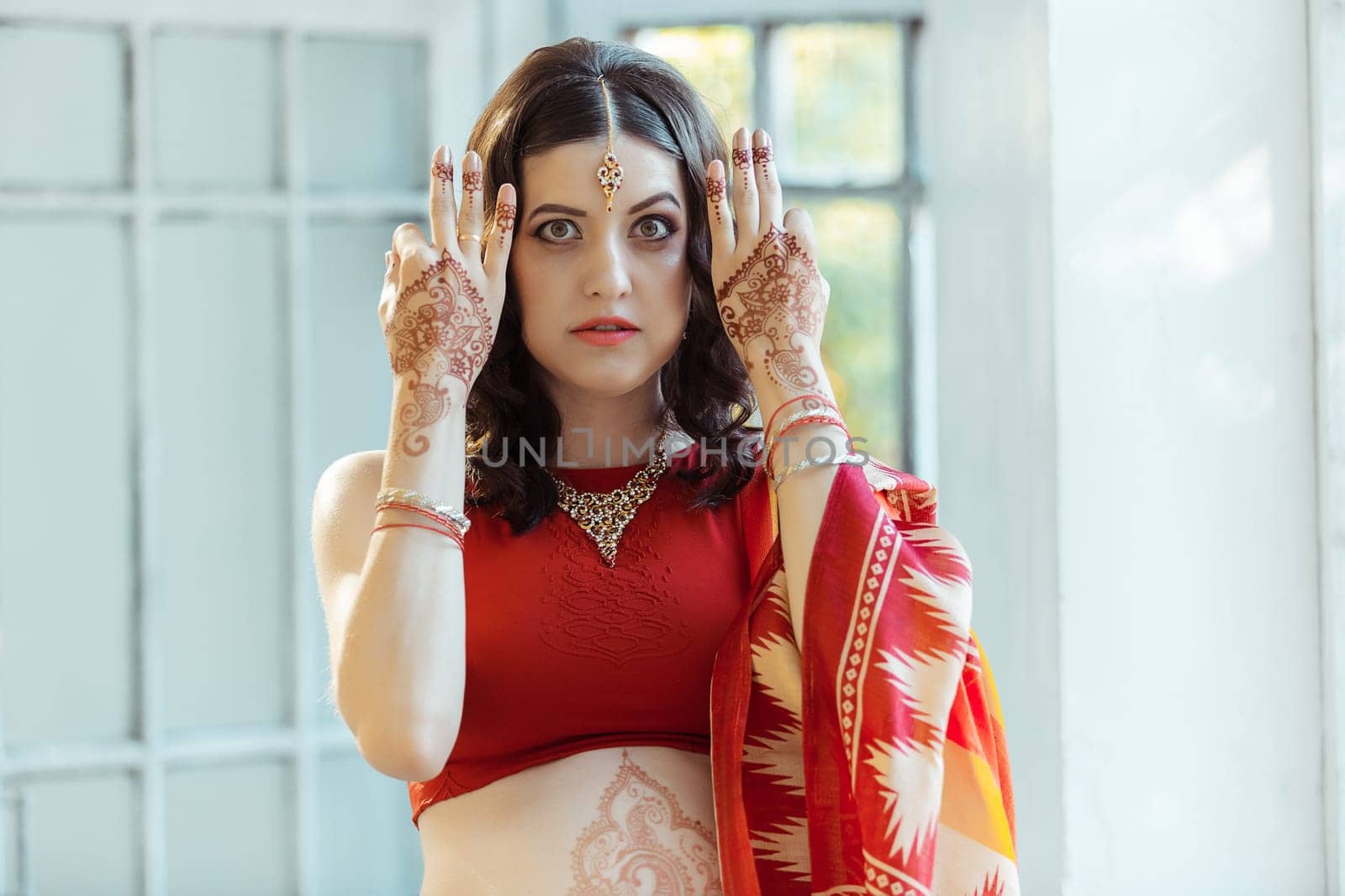 Indian picture on woman hands and belly, mehendi tradition decoration, resistant design by brown henna on white room background