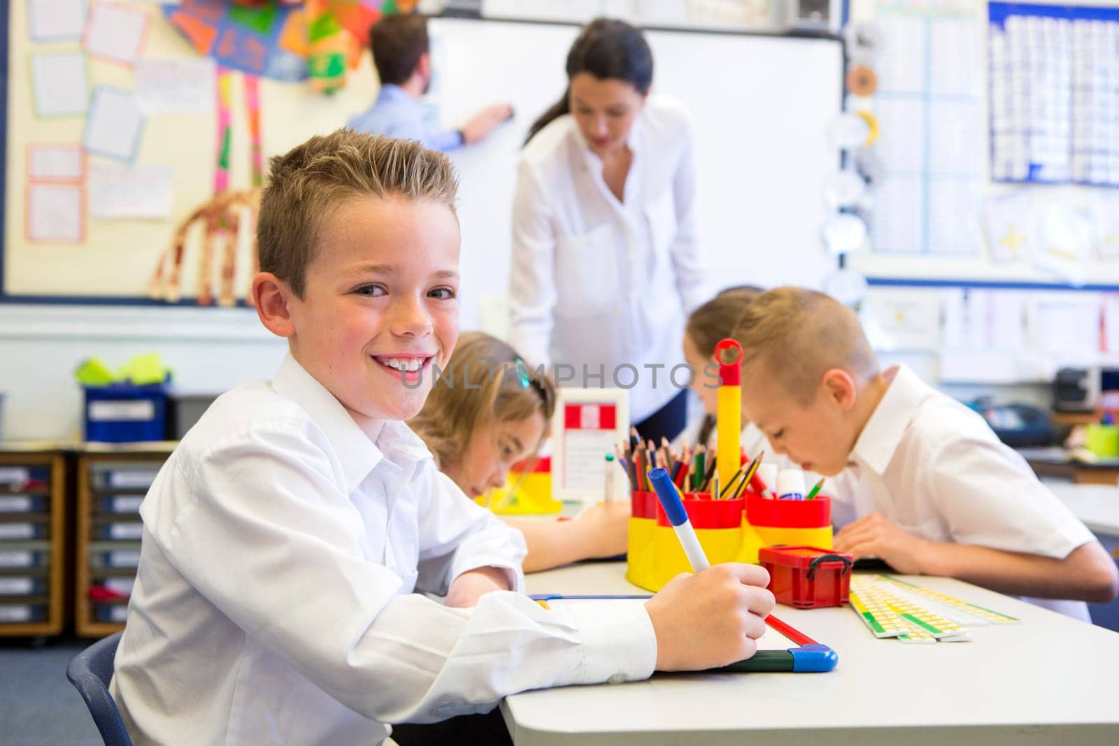 Portrait of a cute young schoolboy smiling at the camera while sitting at his desk.