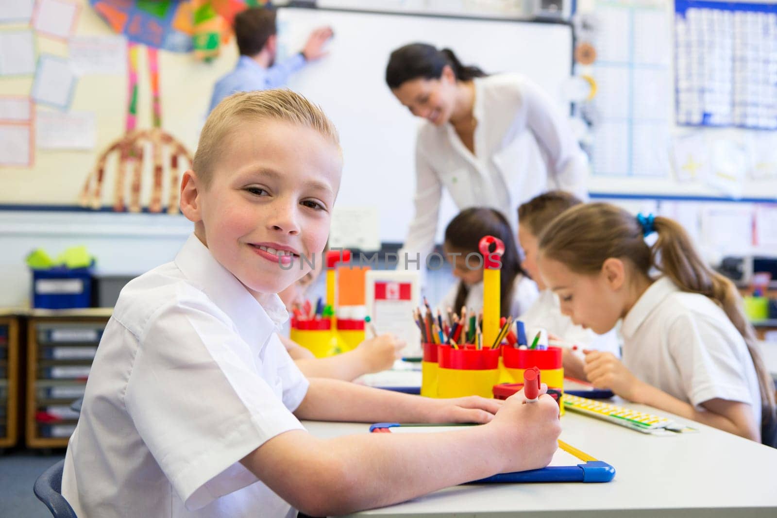 Portrait of a cute young schoolboy smiling at the camera while sitting at his desk.