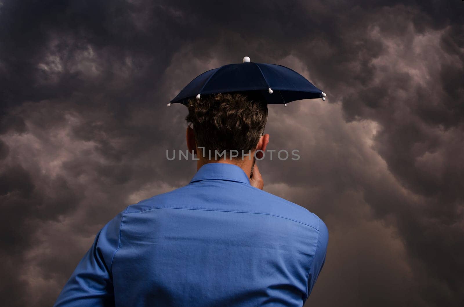 Business man with small umbrella in front of a heavy storm