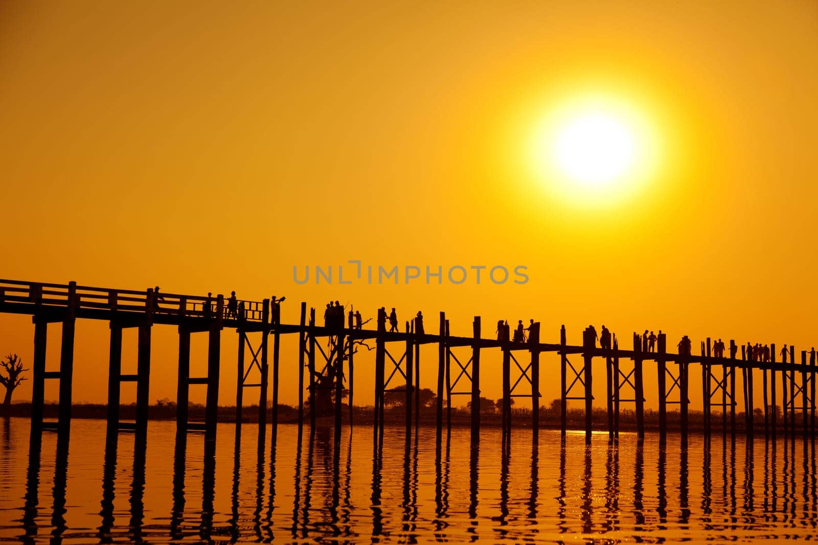U Bein Bridge at sunset with people crossing Ayeyarwady River, Mandalay, Myanmar
