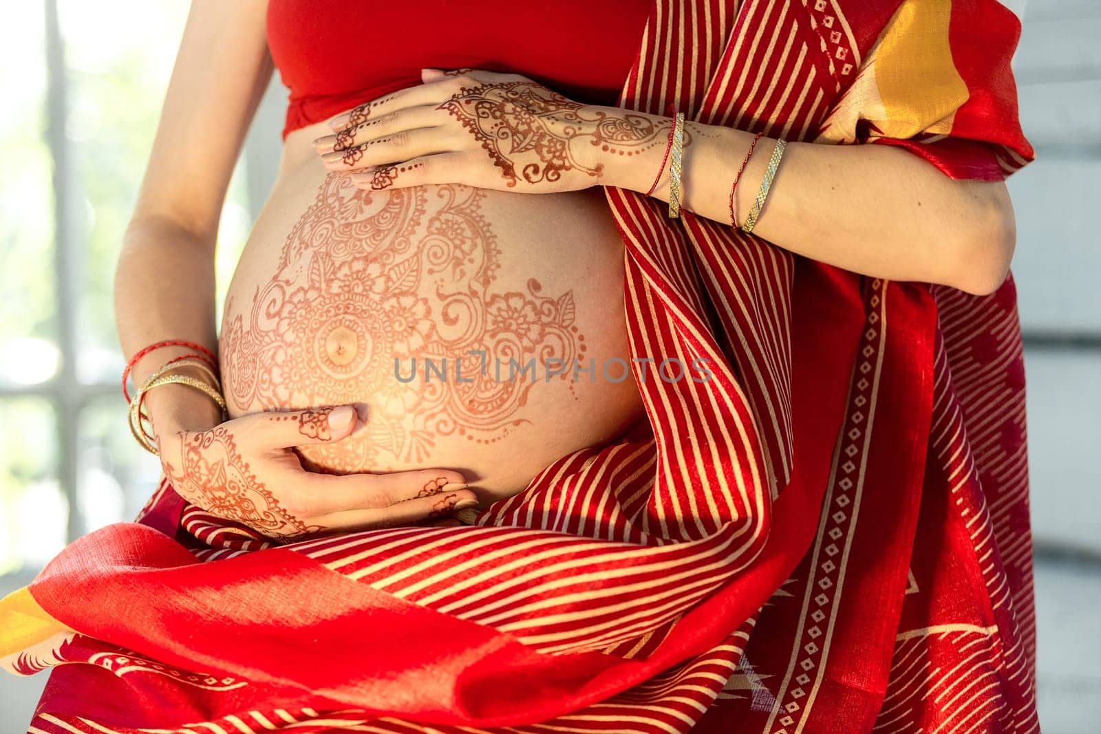 Indian picture on woman hands and pregnant belly with henna tattoo  on white room background