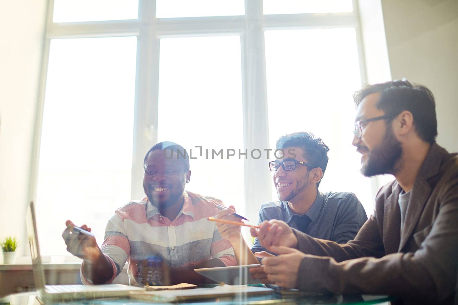 Group of employees pointing at laptop display while discussing project