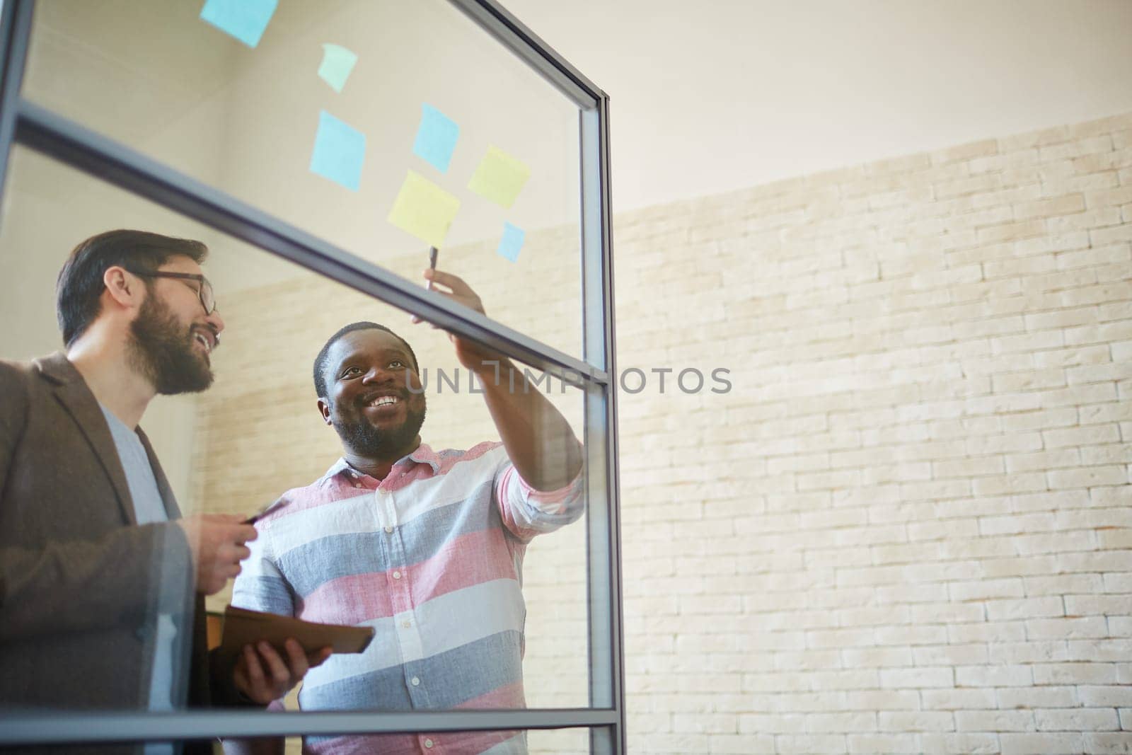 African businessman pointing at reminder with his colleague near by