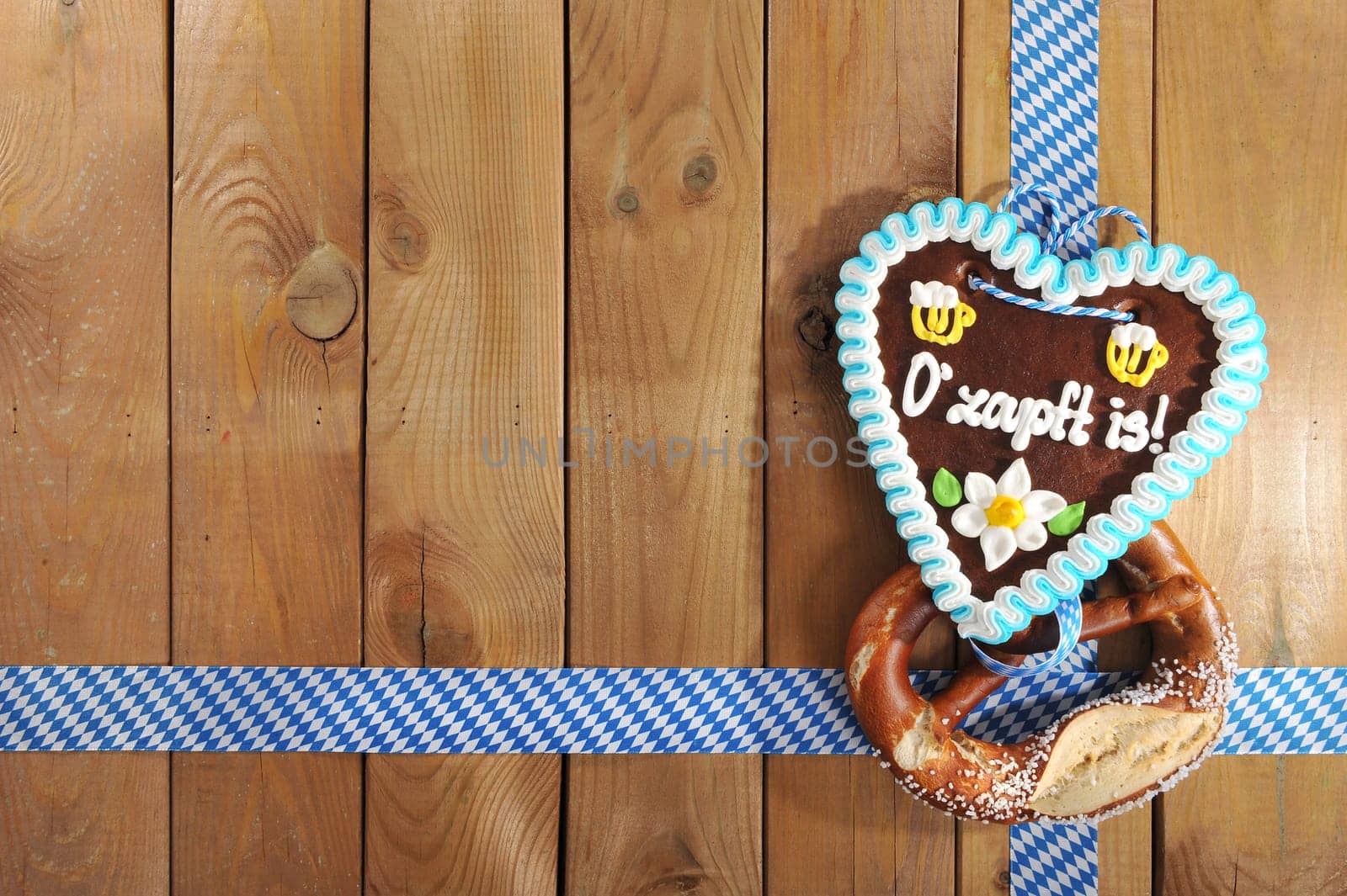 O'zapft is! - original Bavarian lye pretzel with Oktoberfest gingerbread heart in front of a wooden wall