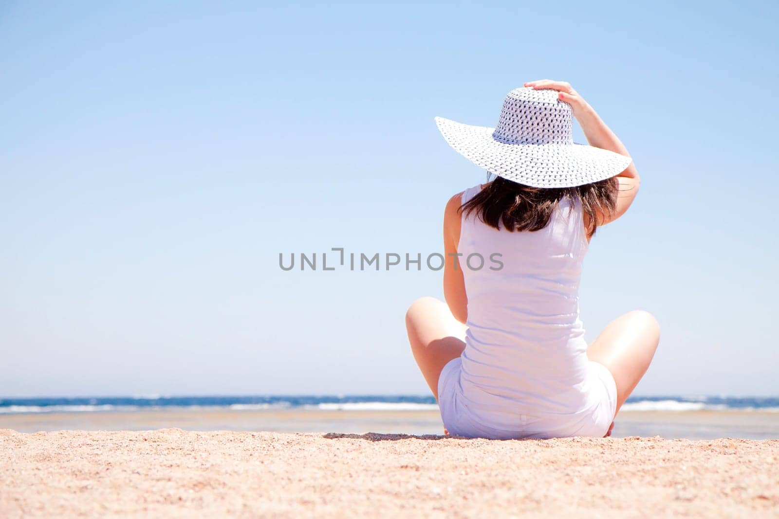 young woman sitting on the sand at the beach