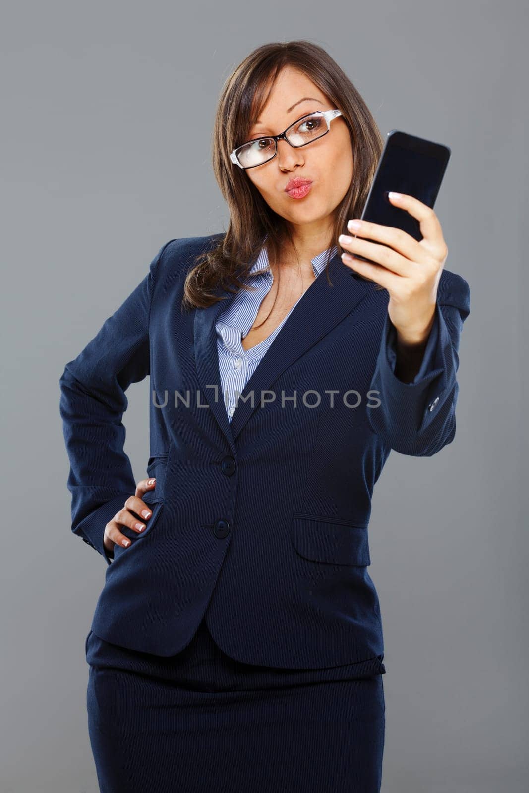 Businesswoman making a face and photographing self with a mobile phone